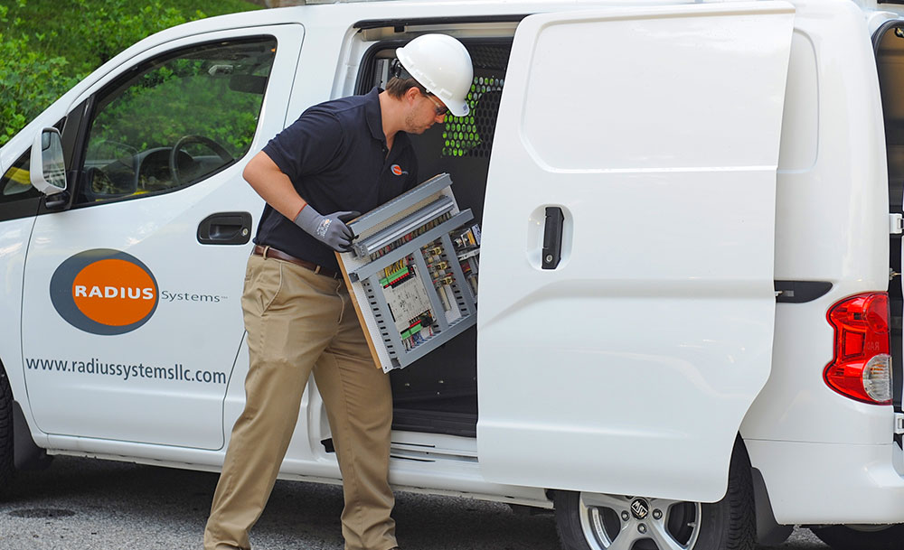 Radius Systems technician loading an Automated Logic panel into a service van