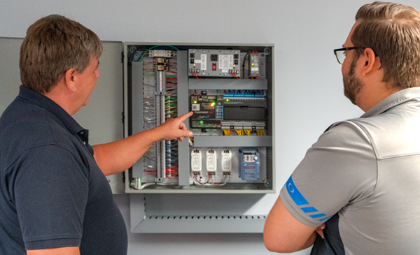 Building Automation Systems Engineer examines BAS panel with customer Building Automation Systems Engineer examines BAS panel with customer